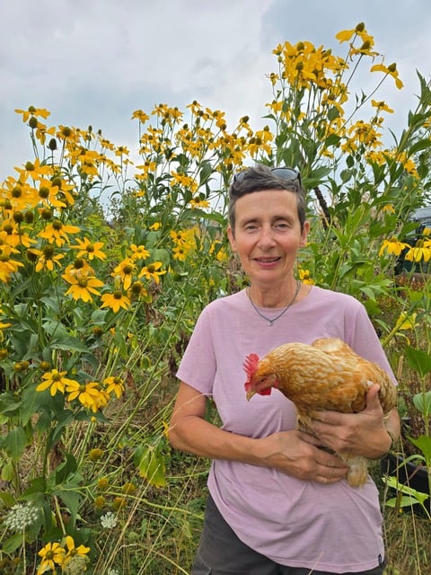 Claudia Stein mit einer Henne auf dem Hof
